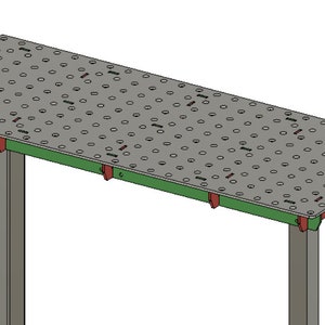 May include: A grey metal welding table with a green painted edge and a grid of holes on the surface. The table has two grey metal legs.
