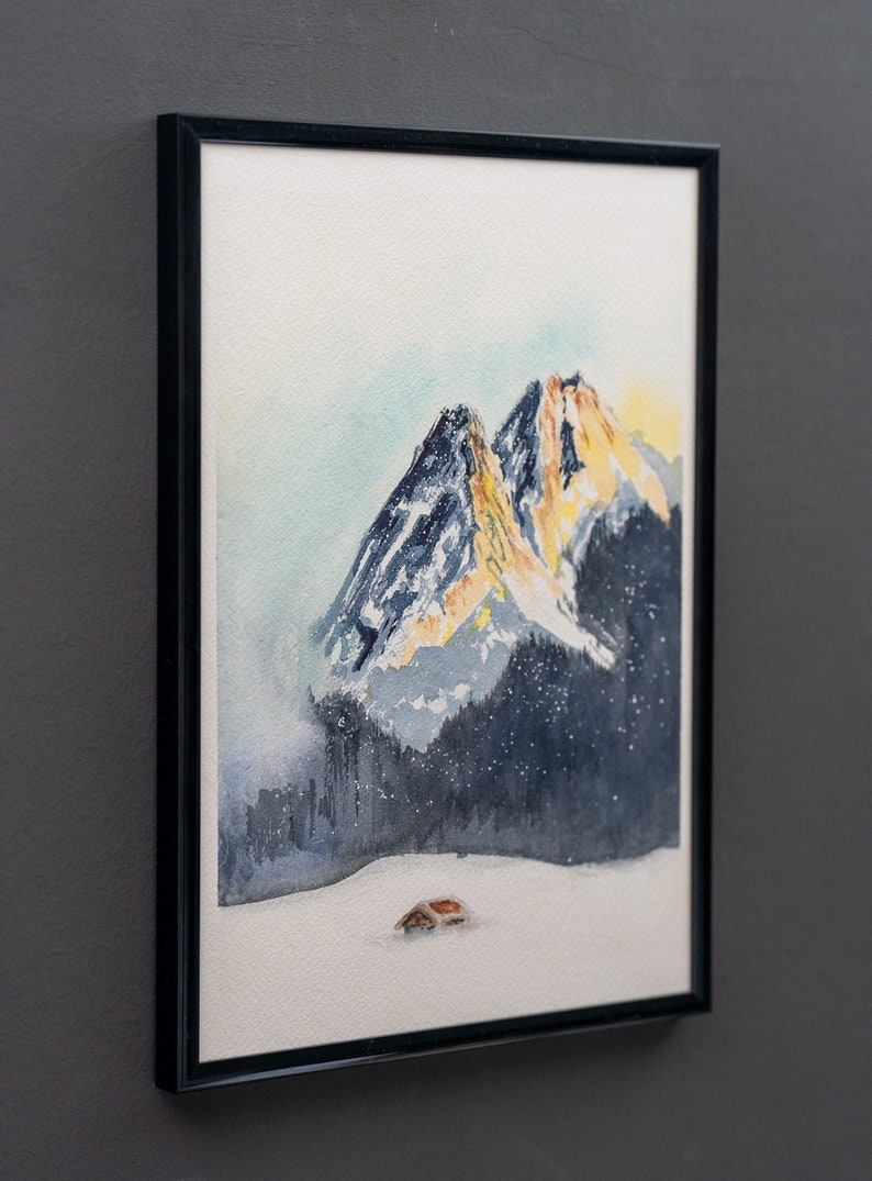 Watercolor painting of the sun setting behind the Garmisch-Partenkirchen mountains, featuring vibrant orange peaks against a darkening blue sky, with a small cabin in the snowy foreground.