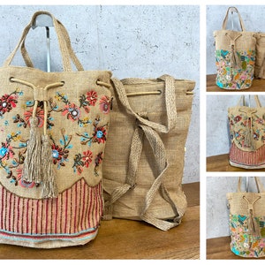 Pode incluir: Quatro sacolas de juta marrom com desenhos florais bordados e borlas. As sacolas têm fecho de cordão e são feitas de materiais naturais.