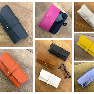 Peut inclure: Assortiment de huit étuis à lunettes en cuir de différentes couleurs, notamment noir, rose, argent, jaune, marron, blanc, bleu et orange. Chaque étui est doté d'une fermeture à pression dorée et d'une finition en cuir texturé.