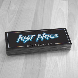 May include: A stack of black stickers with a blue and white graphic that says "last place" and the text "地雷の よう に 強い です" in Japanese.