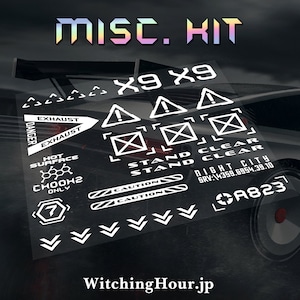 May include: A set of white vinyl decals with various warning signs, including "Exhaust", "Hot Surface", "Caution", "Stand Clear", and "Night City". The decals also include a number "7" in a circle, a chemical formula "CHOOH2", and the text "X9 X9".