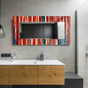 May include: A bathroom vanity with a white countertop and wooden cabinets. A mirror with a colorful, striped frame hangs above the sink. The mirror reflects the bathroom's interior.