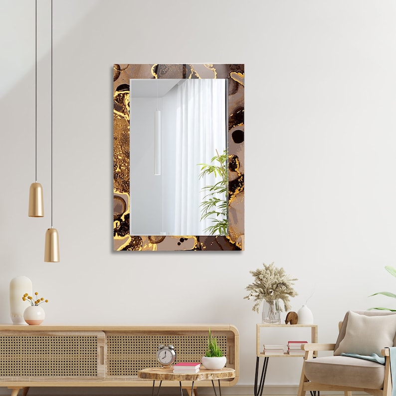 May include: A rectangular mirror with a brown and gold abstract design frame. The mirror is reflecting a white wall and a white curtain.