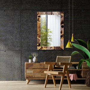 May include: A brown wooden console table with a chair in front of it. The table has two drawers and a shelf. The chair has a woven cane seat and back. A mirror with a gold and brown abstract design hangs on the wall behind the table. Two yellow pendant lights hang from the ceiling.