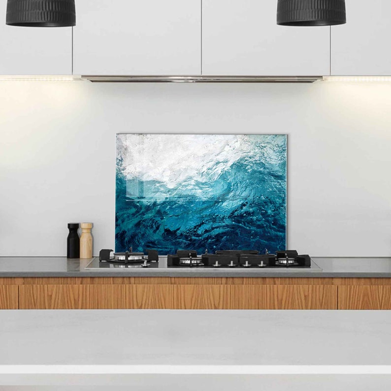 May include: A blue and white abstract wave design glass kitchen backsplash. The backsplash is installed above a gas stovetop.