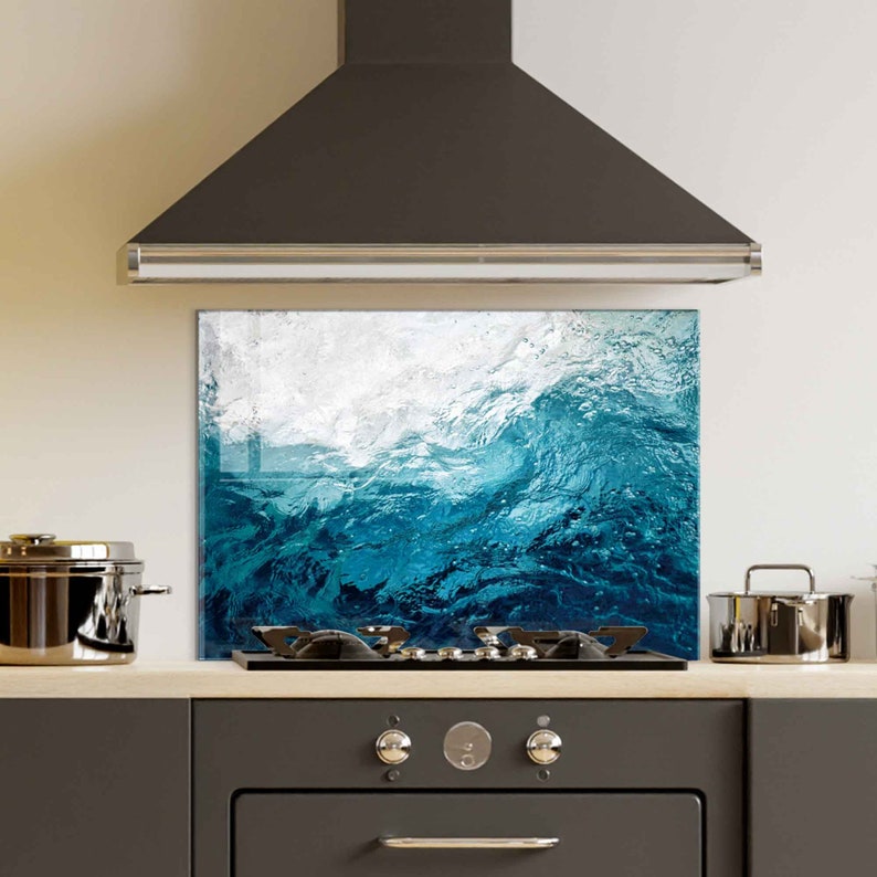 May include: A blue and white glass splashback with a wave design. The splashback is installed above a gas stove in a kitchen.