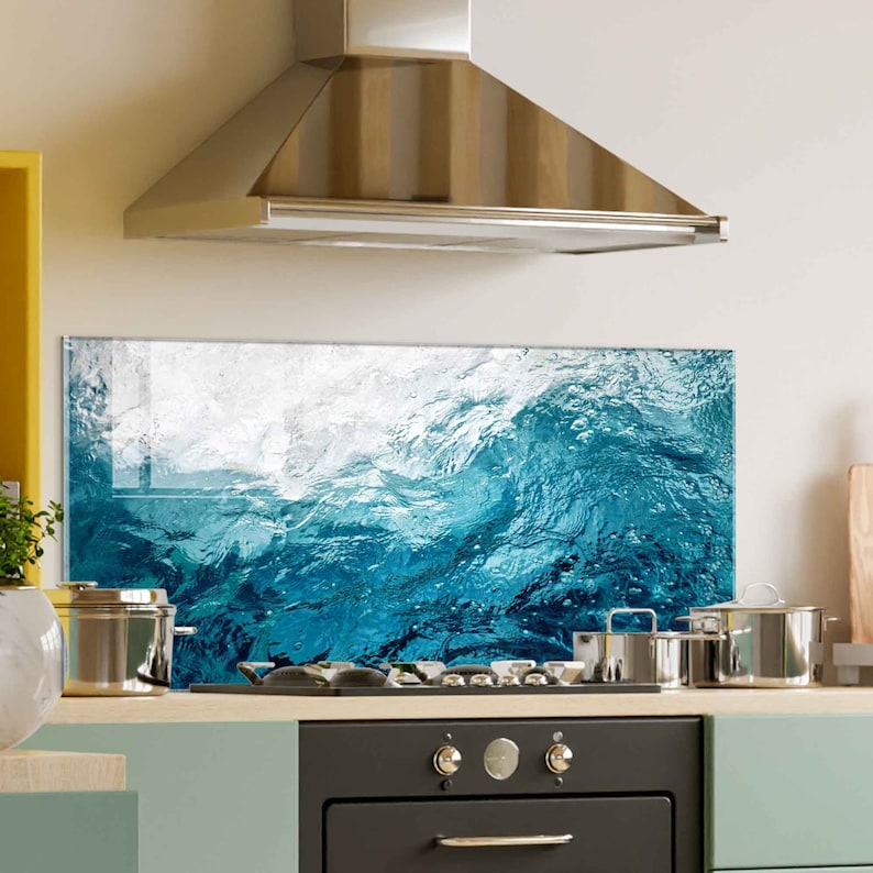 May include: A blue and white abstract wave design kitchen backsplash. The backsplash is installed behind a black stove with a stainless steel range hood above.