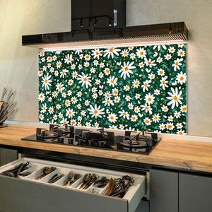 May include: A kitchen backsplash with a green background and a white daisy pattern. The backsplash is installed above a black gas hob.