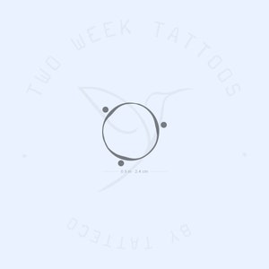 Peut inclure: Un design de tatouage simple en forme de cercle avec quatre petits points autour du cercle. Le motif mesure 0,9 pouce ou 2,4 cm de diamètre. Le texte "Two Week Tattoos by Tatteco" est écrit autour du cercle.