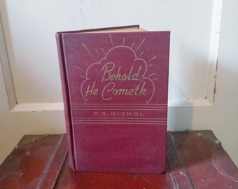 May include: A burgundy hardcover book with gold lettering on the front cover. The title of the book is "Behold He Cometh" by F.D. Nichol.