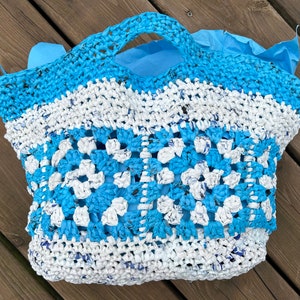 May include: A blue and white crocheted tote bag with a square pattern. The bag is made from recycled plastic.
