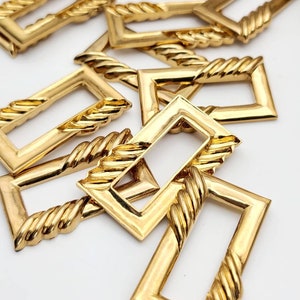 May include: A group of gold-colored metal rectangular frames with a rope-like design around the edges. The frames are arranged in a pile, with some overlapping.