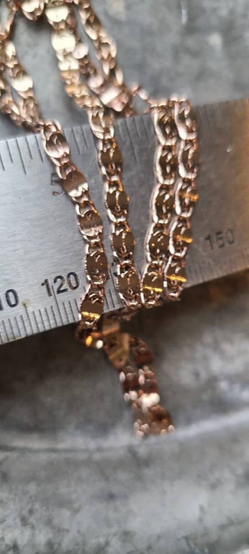Puede incluir: Primer plano de un collar de cadena de oro con un delicado patr&oacute;n de eslabones ovalados. La cadena se mide con una regla, mostrando la longitud en pulgadas.