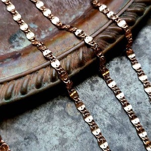 Puede incluir: Dos cadenas de oro con un patr&oacute;n ovalado enlazado yacen sobre una superficie marr&oacute;n texturizada. Las cadenas est&aacute;n hechas de un metal brillante y tienen un dise&ntilde;o cl&aacute;sico.