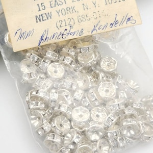 May include: A bag of 7mm clear rhinestone rondelles. The bag is labeled with the company name, address, and phone number.  The label also says "7mm Rhinestone Rondelles".