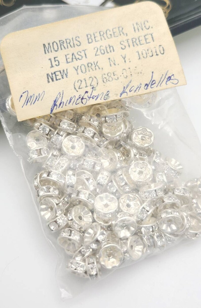 May include: A bag of 7mm clear rhinestone rondelles. The bag is labeled with the company name, address, and phone number.  The label also says "7mm Rhinestone Rondelles".