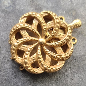 May include: Gold-toned metal flower-shaped connector with intricate details and a beaded edge. The connector has three loops for attaching jewelry pieces.