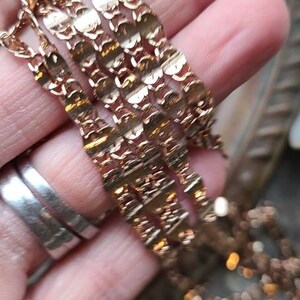 Puede incluir: Primer plano de un collar de cadena de oro con un dise&ntilde;o delicado e intrincado. La cadena est&aacute; en capas y parece estar hecha de m&uacute;ltiples hebras.