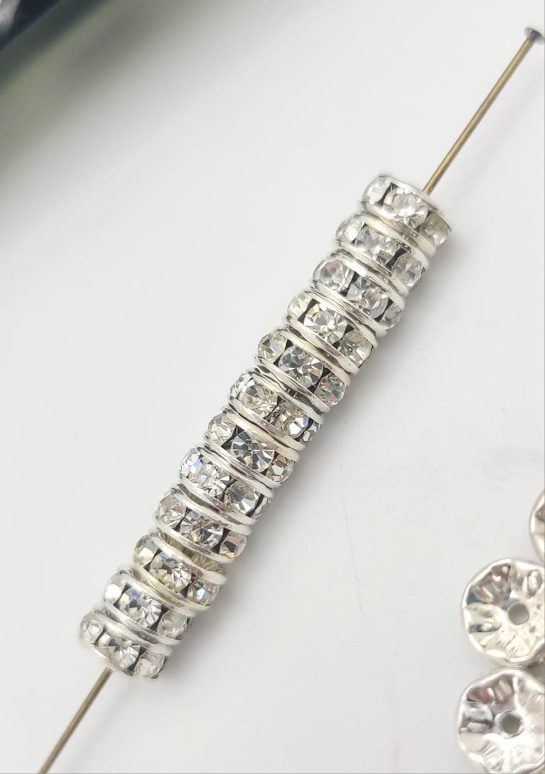May include: A strand of silver-toned spacer beads with clear rhinestones. The beads are strung on a wire and are ready to be used in jewelry making.