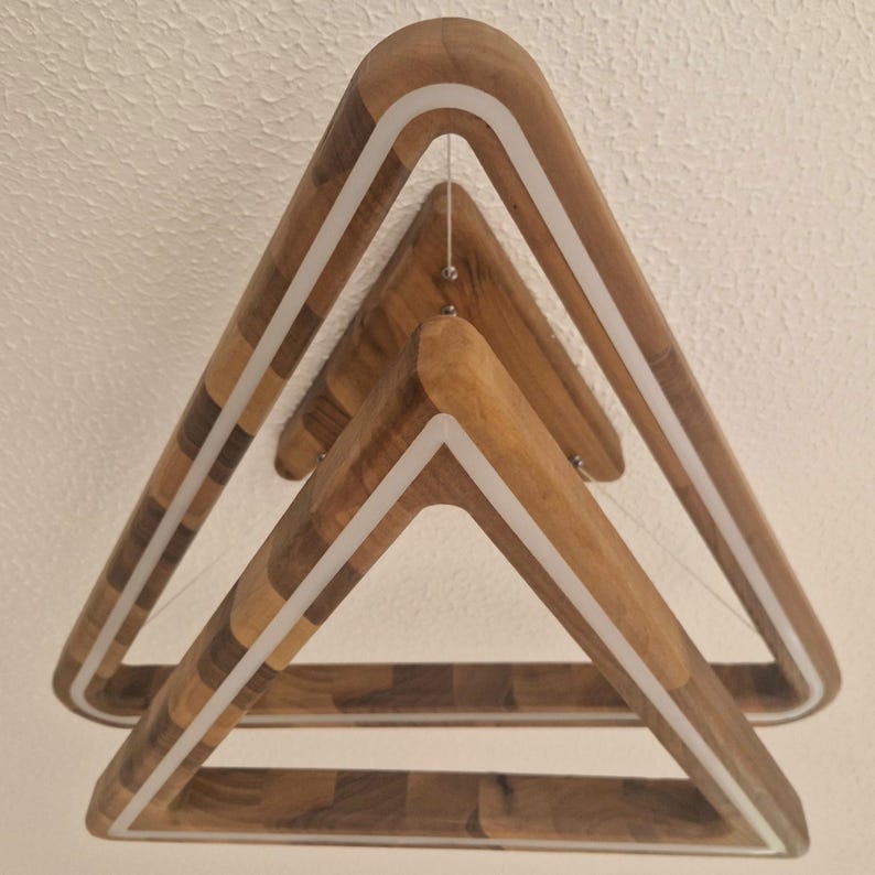 May include: A wooden triangle pendant light with a white LED strip around the perimeter. The light is made of three stacked triangles, each with a different wood grain pattern.