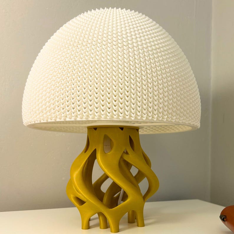 May include: A white mushroom-shaped lamp with a textured dome and a yellow, intricate base.