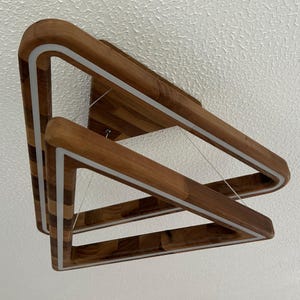 May include: A modern wooden light fixture with two triangular frames. The frames are made of dark wood with a light wood inlay. The fixture has a white LED light strip around the perimeter of each frame.