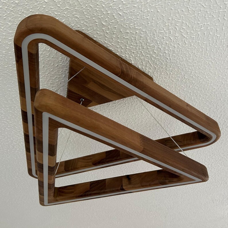 May include: A modern wooden light fixture with two triangular frames. The frames are made of dark wood with a light wood inlay. The fixture has a white LED light strip around the perimeter of each frame.