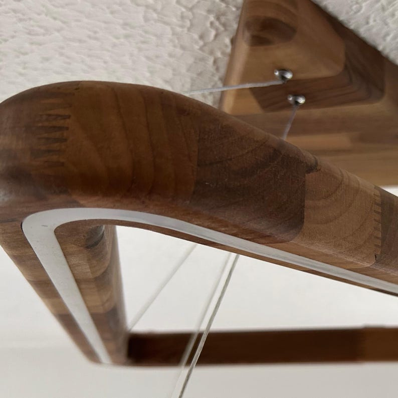 May include: Close-up of a wooden light fixture with a white trim. The fixture is suspended from the ceiling by thin wires.