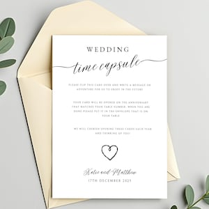 May include: A white wedding time capsule card with black script and a heart graphic, inside a cream envelope. The card reads "Wedding Time Capsule" and includes instructions for guests to write a message for the future. The card is dated December 17th, 2025.