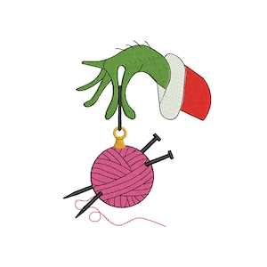 May include: A green hand wearing a red Santa hat holds a pink yarn ball ornament with black knitting needles sticking out.