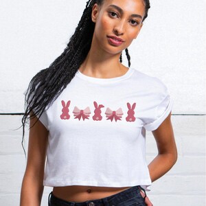 Op de afbeelding: Wit gecropped T-shirt met een rij roze konijnen die roze strikjes dragen.