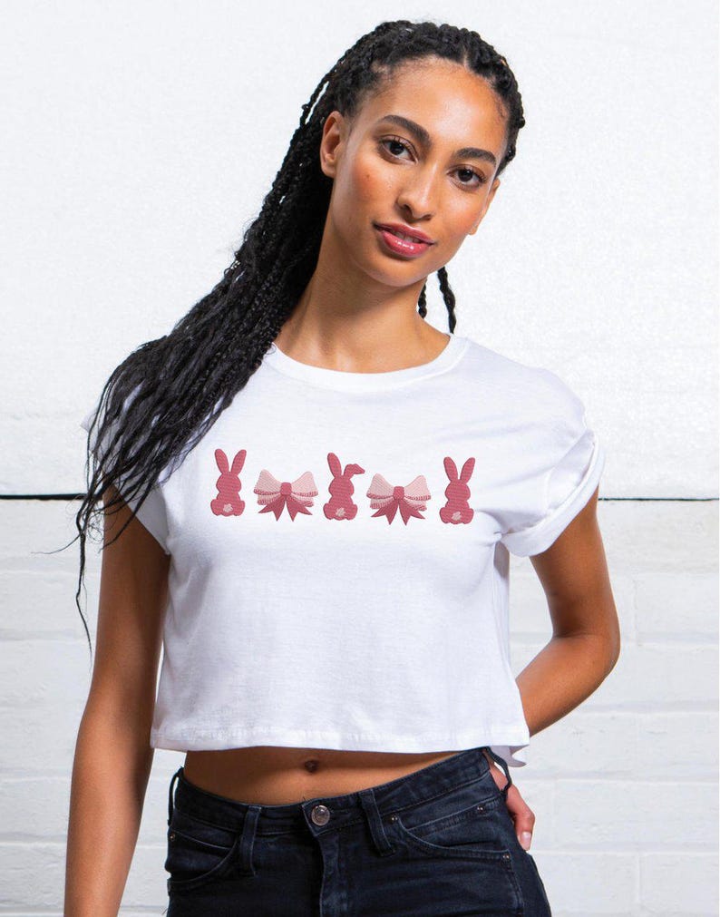 Op de afbeelding: Wit gecropped T-shirt met een rij roze konijnen die roze strikjes dragen.