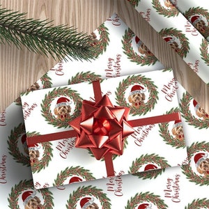May include: White wrapping paper with a repeating pattern of a dog wearing a Santa hat in a Christmas wreath with the text "Merry Christmas".