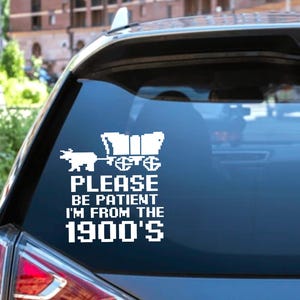 May include: A white vinyl sticker with a pixelated image of a covered wagon pulled by an ox. The text reads "Please be patient I'm from the 1900's".