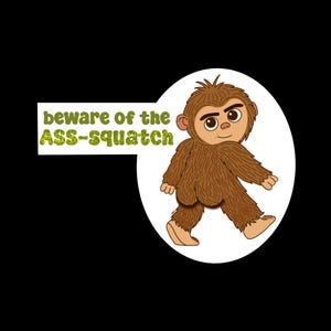 May include: A cartoon illustration of a brown, furry Sasquatch character with a smiling face, set against a white circle. The text "beware of the ASS-squatch" is displayed in a green, glittery font on a white rectangle.