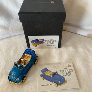 May include: A blue and gold miniature car with a white interior and a blue and gold box. The box has the text "The People's Car" and "Release No. 401" on it.