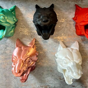 May include: Five animal head sculptures in different colours. The sculptures are made of a smooth, glossy material and have a realistic appearance. The colours are green, black, red, copper, and white.