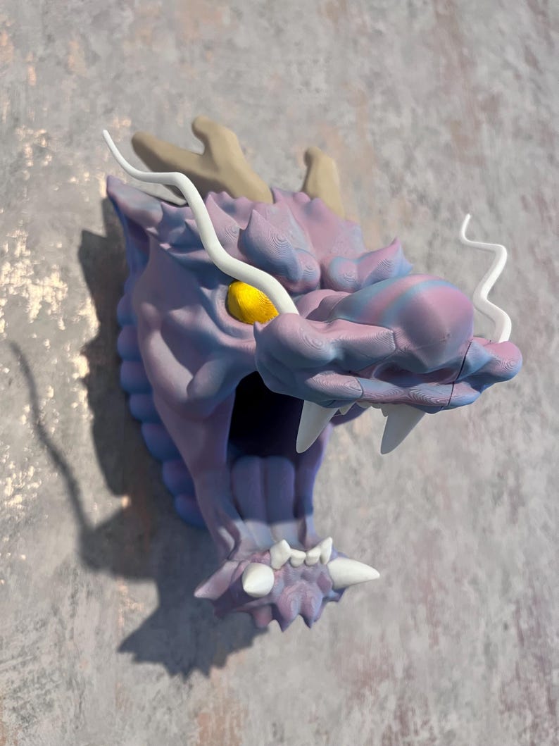 May include: Purple and blue dragon head wall sculpture with white horns and a yellow eye. The dragon's mouth is open and has white teeth.