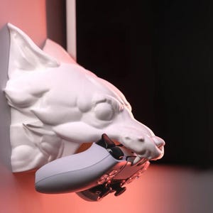May include: A white ceramic wolf's head wall mount with a grey video game controller in its mouth.