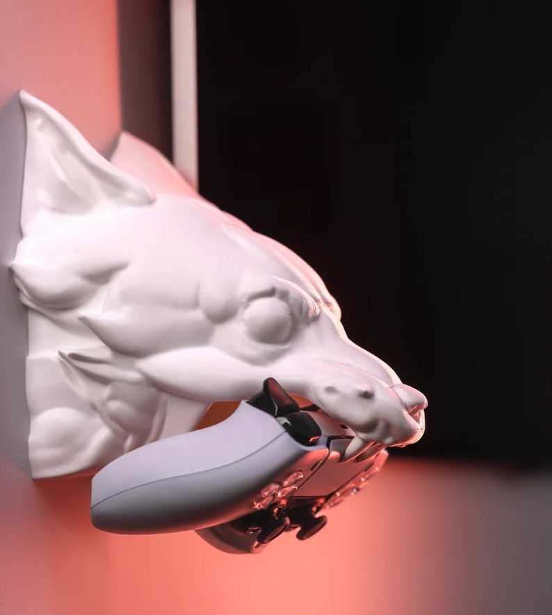 May include: A white ceramic wolf's head wall mount with a grey video game controller in its mouth.