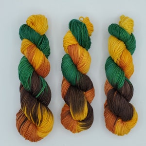 May include: Three skeins of yarn in shades of brown, green, and yellow. The yarn is twisted into a rope-like shape.