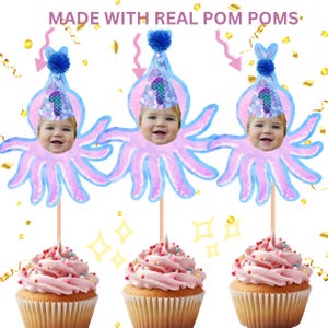May include: Three pink and blue octopus cupcake toppers with a child's face in the center of each octopus. Each octopus has a blue and purple hat with a number one on it. The toppers are on top of cupcakes with pink frosting and colorful sprinkles.