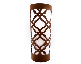 May include: A brown metal candle holder with a geometric design. The holder is cylindrical and has a white candle inside.