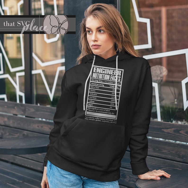 Op de afbeelding: Zwarte hoodie met een witte afbeelding van een voedingswaardelabel voor een ingenieur. Het label vermeldt toewijding, cafe&iuml;ne en spijt als ingredi&euml;nten.