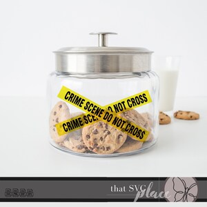 May include: A glass cookie jar with a silver lid and yellow crime scene tape that reads "Crime Scene Do Not Cross". The jar is filled with chocolate chip cookies.