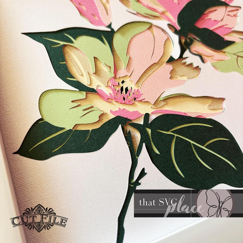 May include: A layered paper flower with pink, green, and yellow hues. The flower has detailed petals and is set against a soft, off-white background. Dark green leaves and stem support the flower. The text "CUT FILE" and "that SVG place" are visible.