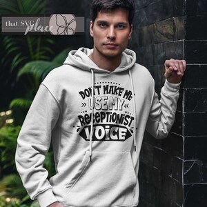 Op de afbeelding: Witte hoodie met de tekst "Don't make me use my receptionist voice" in zwarte letters.