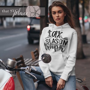 May include: White hoodie with black text that reads "tax season trooper" on the front. The hoodie is being worn by a person sitting on a motorcycle.