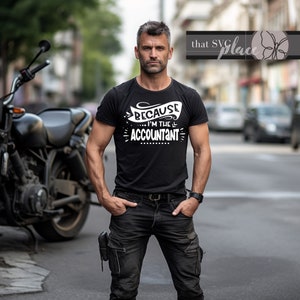 May include: A man wearing a black t-shirt with white text that reads "Because I'm the Accountant". He is standing in front of a motorcycle.